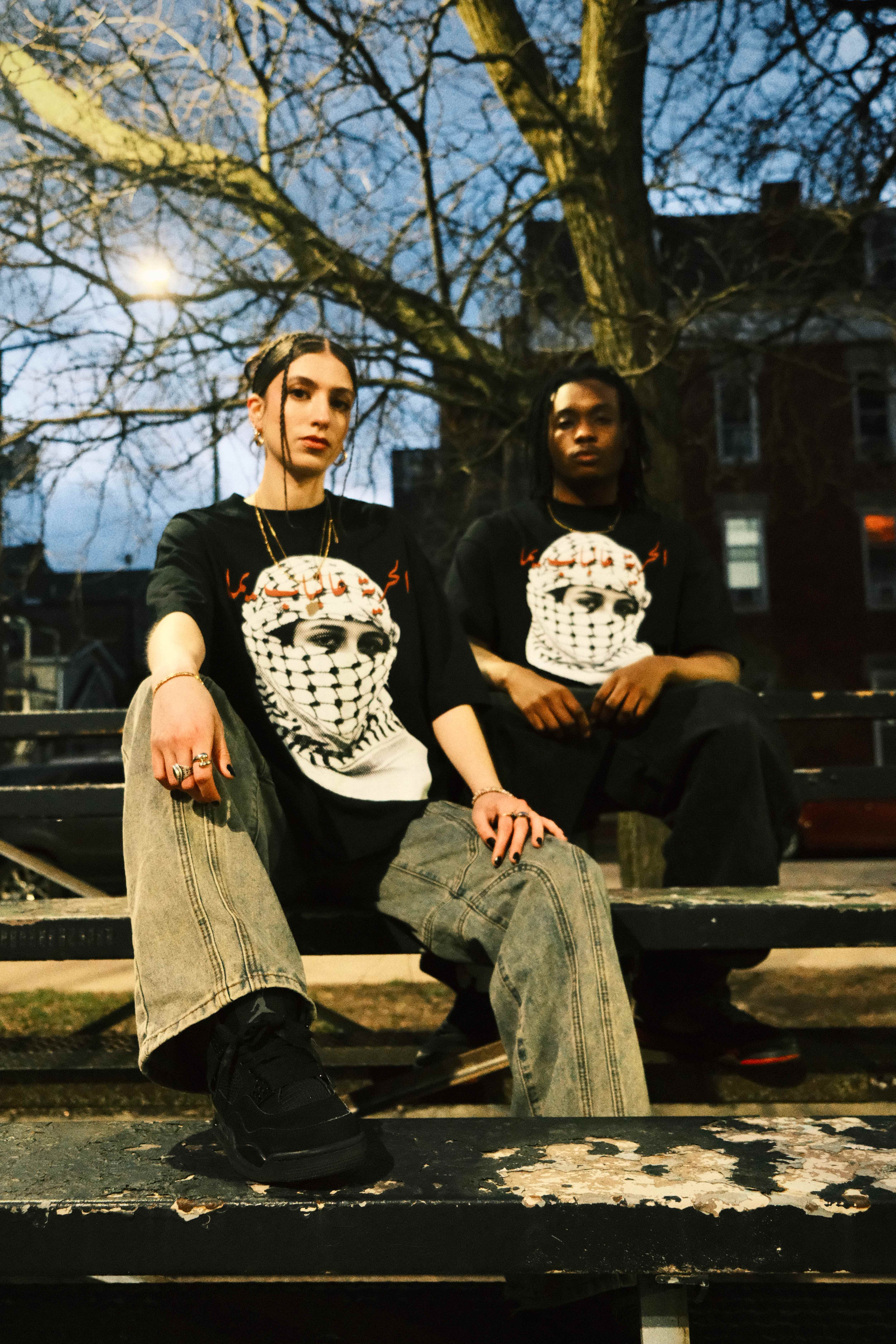 Two people wearing Archive Celine t-shirts sitting on a bench